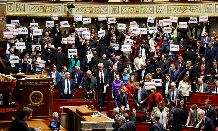 Left-wing coalition NUPES members of parliament hold signs reading "Liberte", "Egalite", "fraternite" French for 'liberty, equality, fraternity', the national motto of France, following the vote and the approval of the draft law to control immigration, at the French National Assembly in Paris. AFP