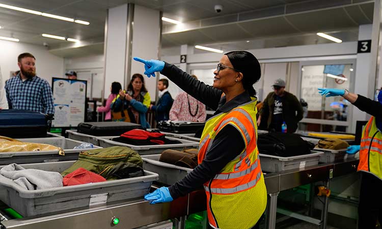 A worker points as people wait for the belongings at the Transportation Security Administration security area at the Hartsfield-Jackson Atlanta International Airport in Atlanta. AP
