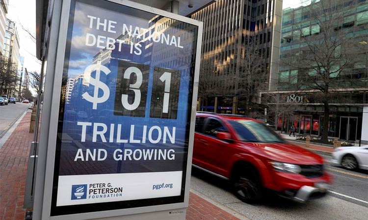 A car drives next to a board at a bus stop showing a U.S. national debt figure. Reuters