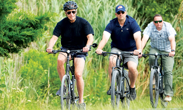 President Joe Biden rides his bike on a bike path at Gordons Pond in Rehoboth Beach, Delaware.  Associated Press
