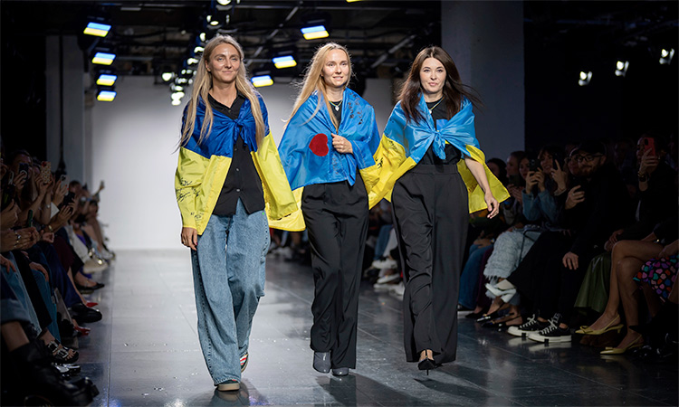 Designers Ksenia Schnaider (left), Nadya Dzyak and Elena Reva walk the catwalk wearing Ukrainian flags in London. AP