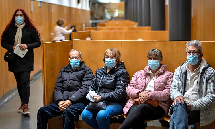 People wearing face masks as a precaution wait for appointments inside a hospital in Barcelona. AP
