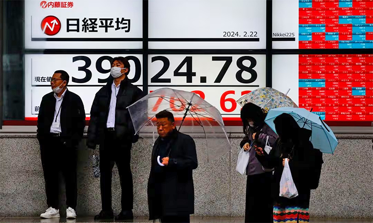 Passersby stand in front of electronic screens displaying Japan's Nikkei share average, which surged past an all-time record high scaled in December 1989, outside a brokerage in Tokyo. Reuters