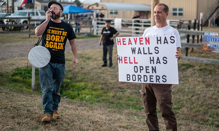Protesters hold up signs and speak through a bullhorn supporting the ‘Take Our Border Back’ convoy near Cornerstone Childrens Ranch near Quemado, Texas.  File/Tribune News Service