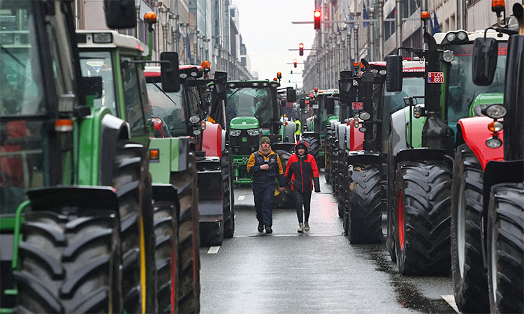 People walk between tractors during a protest of European farmers over price pressures, taxes and green regulation in Brussels, Belgium. Reuters