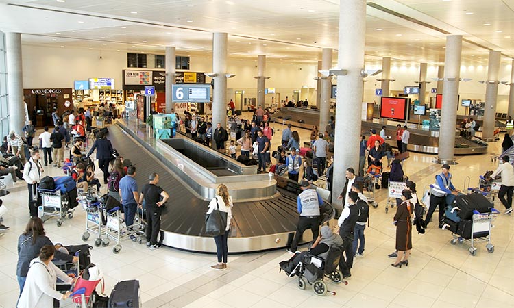 Passengers wait for their luggage near a conveyor belt at the Abu Dhabi Airport.
