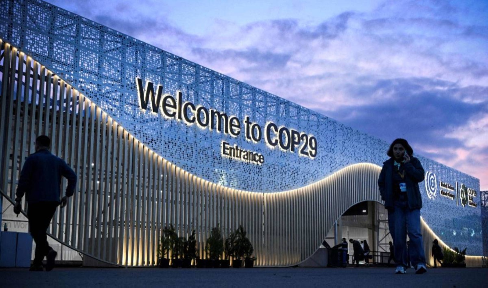 Pedestrians walk in front of the venue for COP29 Summit in Baku on the eve of UN Climate Change Conference (COP29). AFP