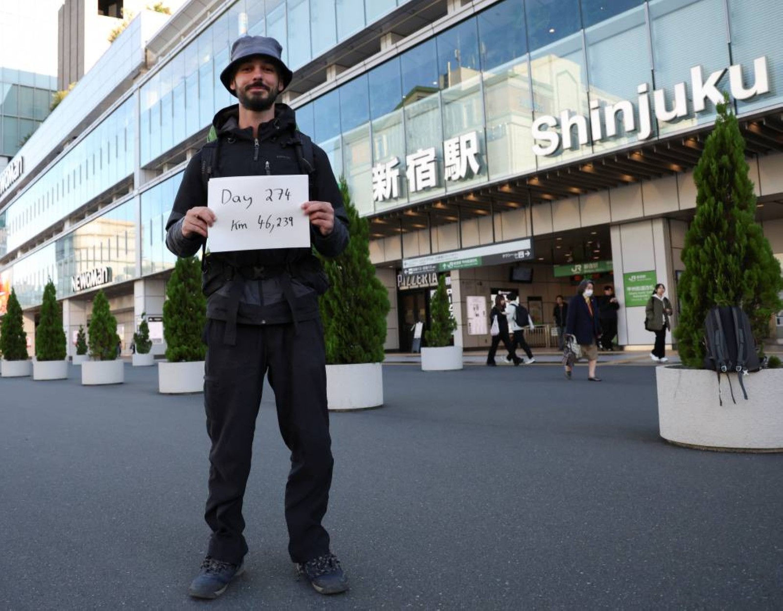 Omar Nok holds a sign noting the days and distance he has travelled in front of Shinjuku station in Tokyo. Reuters 