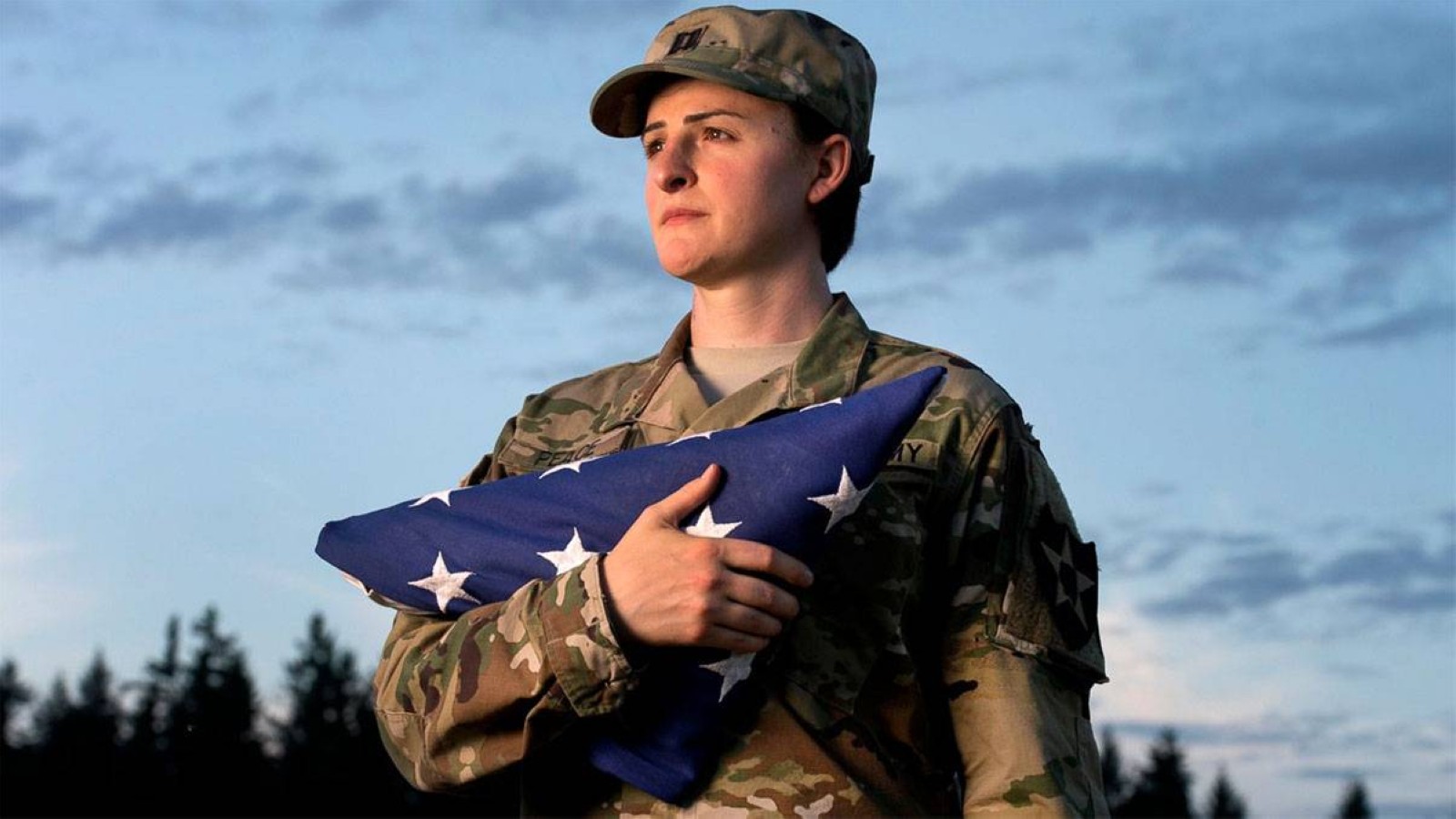 Capt. Jennifer Peace holds a flag as she stands for a photo near her home in Spanaway, Washington. Peace is one of an estimated 15,000 transgender people who serve in the active-duty military. She has been deployed around the world, including Iraq and Afghanistan. File/AP