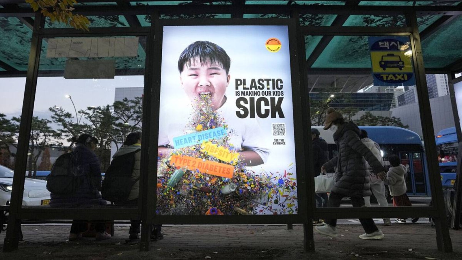 A display board shows a call for a reduction in plastic production during the fifth session of the Intergovernmental Negotiating Committee on Plastic Pollution, at a taxi station in Busan, South Korea. AP
