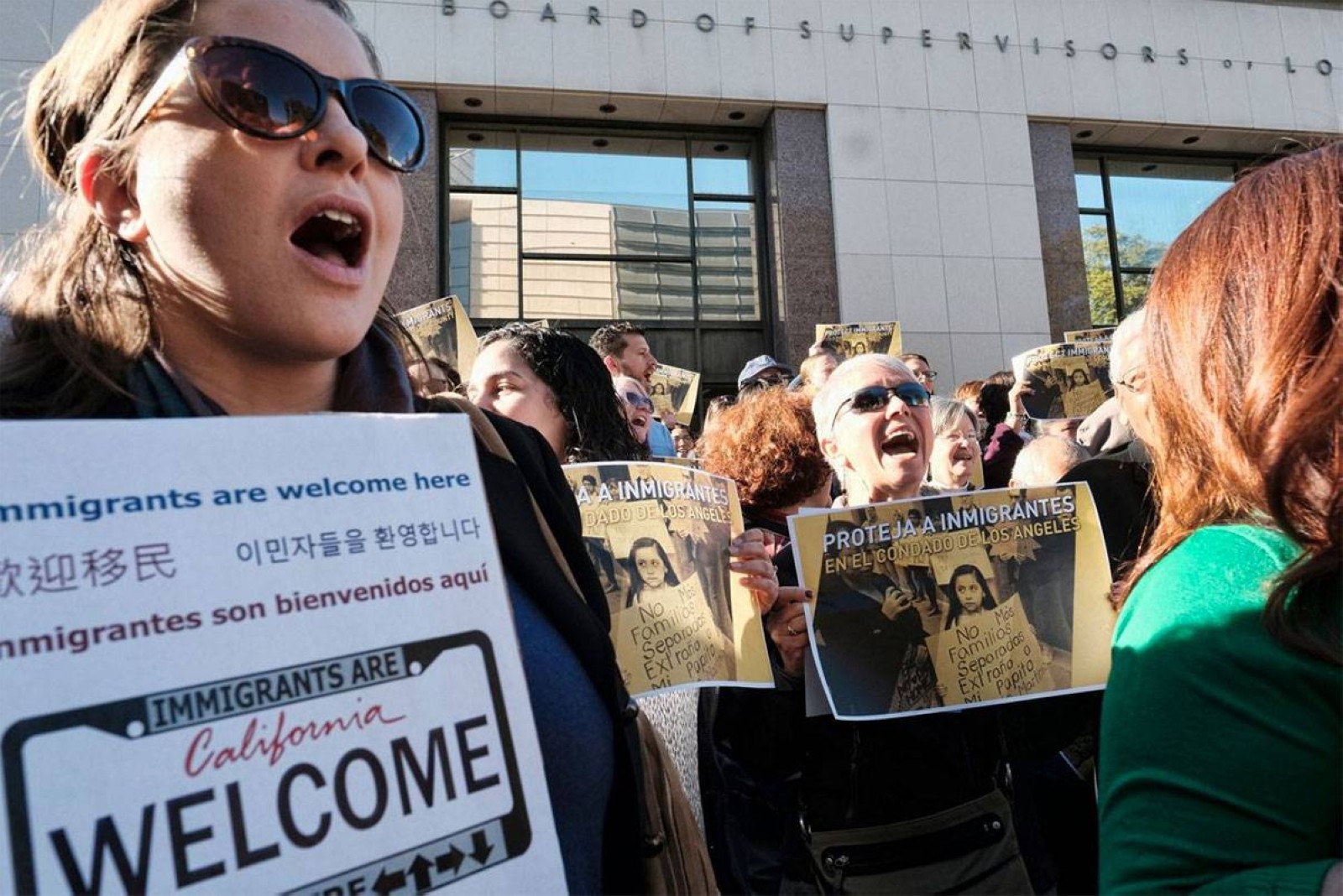 California residents hold placards welcoming immigrants to the state.