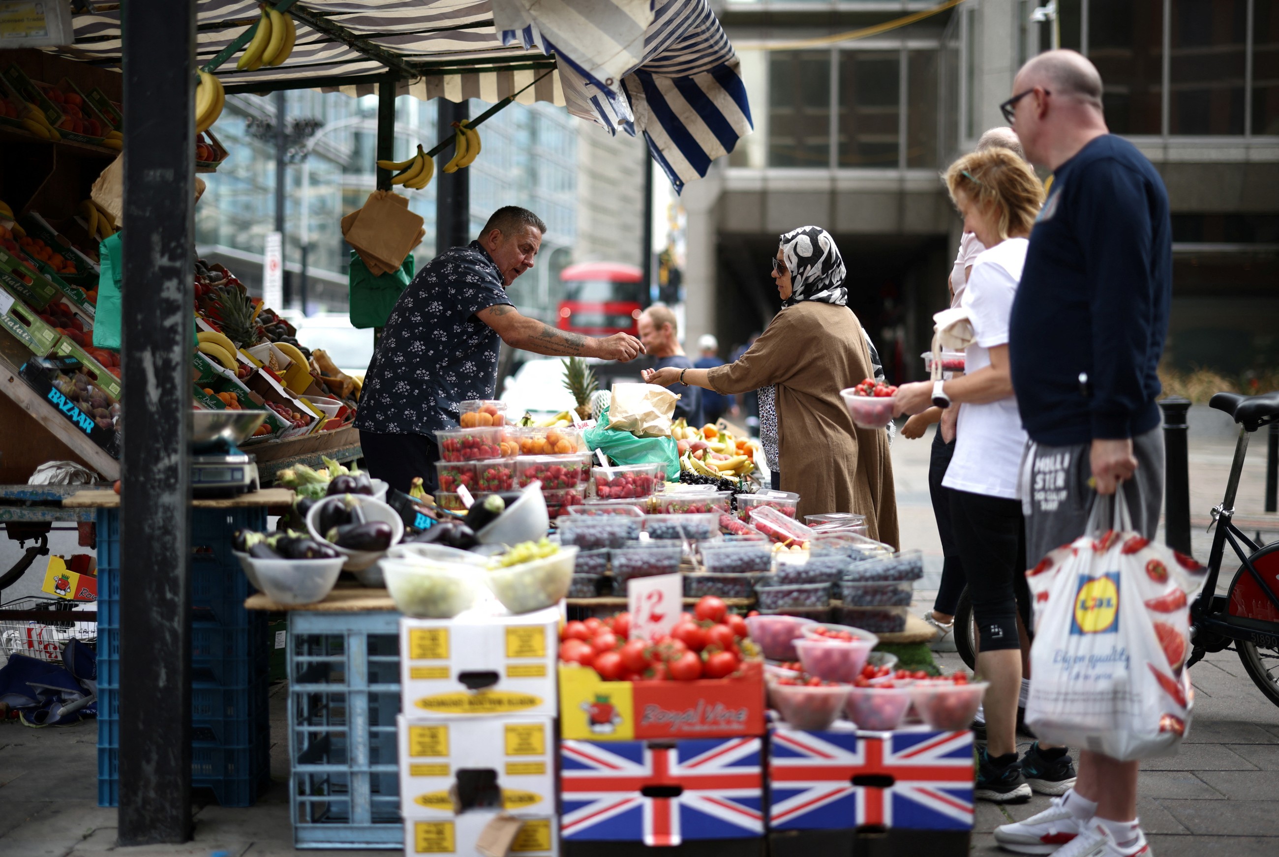 Customers buy fruits and vegetables at a stall in central London, Britain. Reuters