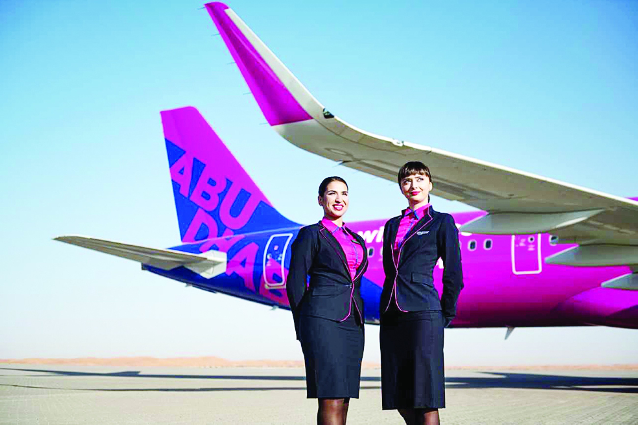 Airhostesses pose for a photograph next to a Wizz Air airline. File