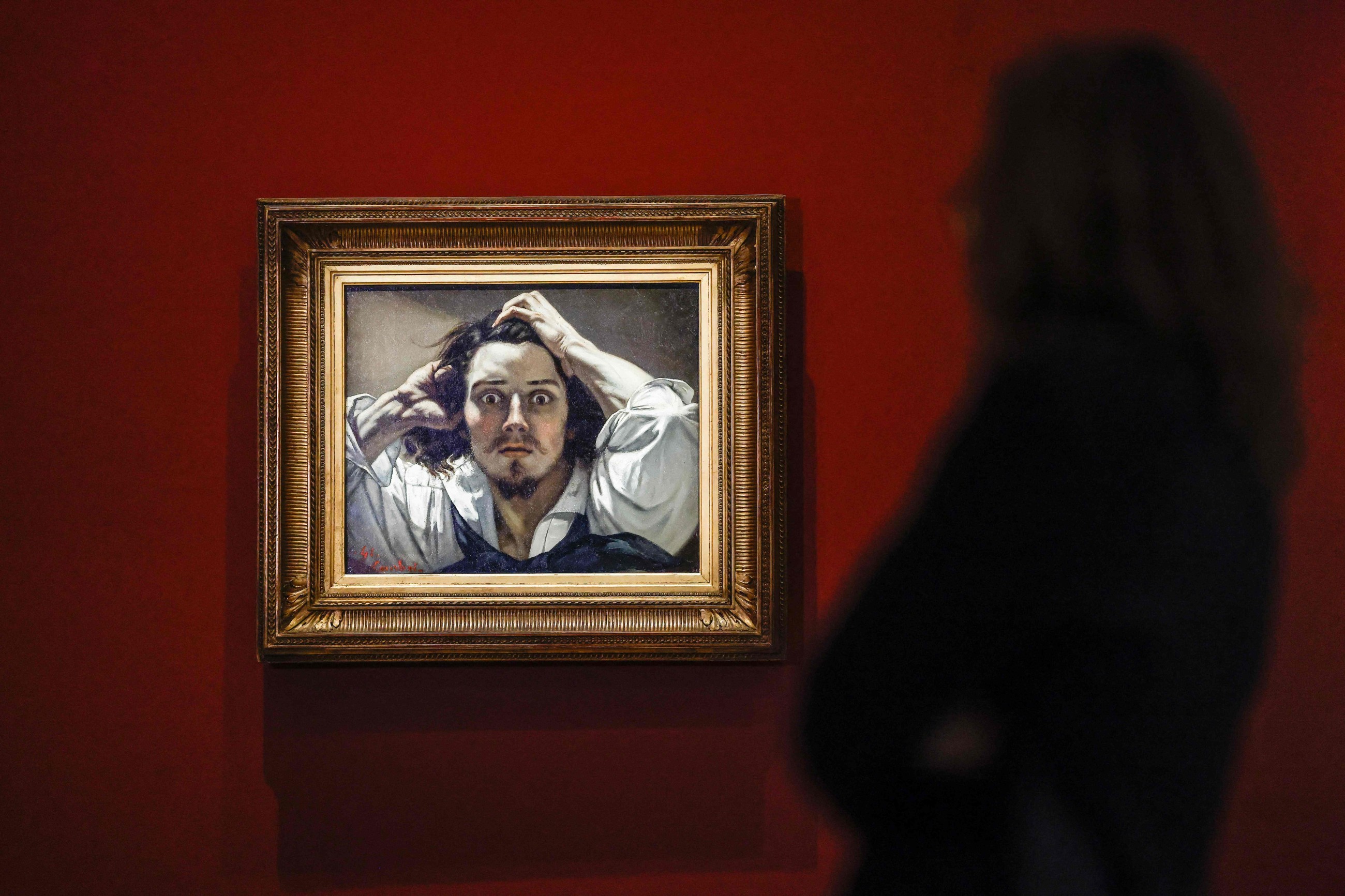 An attendee looks at French painter Gustave Courbet's 'The Desperate Man' exhibited on loan at the Musee d'Orsay in Paris.