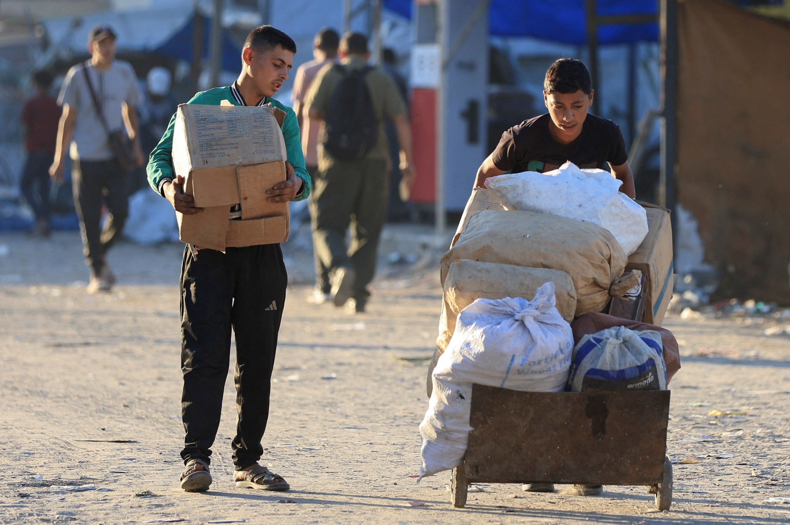 Palestinians carry goods, amid a ceasefire between Israel and Hamas, in Gaza City.