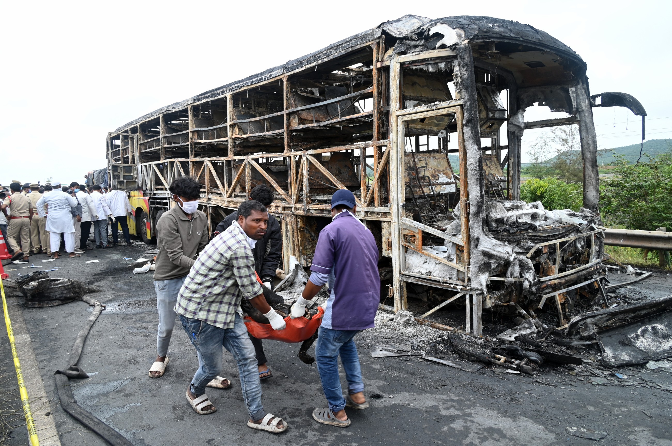 Volunteers remove a body from the debris of a passenger bus which caught fire after a collision with a motorbike on a highway in Chinnatekuru village. AP