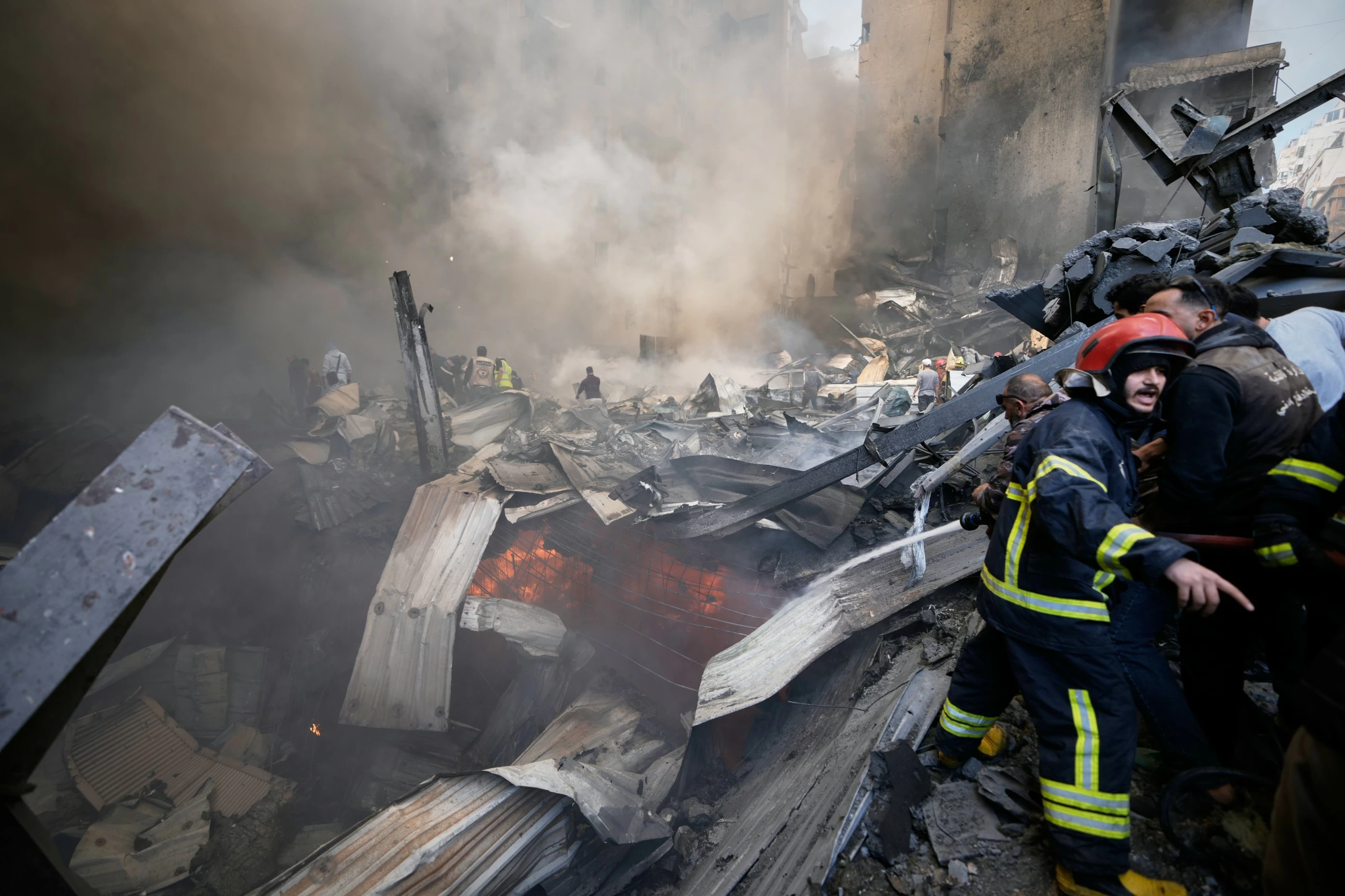 Firefighters and volunteers work on smoldering debris in Beirut.